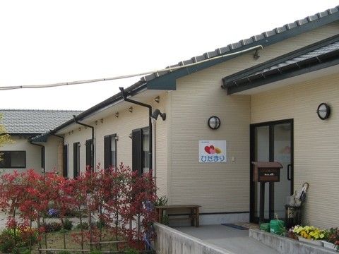 落ち着いた雰囲気の施設外観。入口までのスロープは花壇に囲まれている。中庭にも植樹され、自然豊かな環境である。