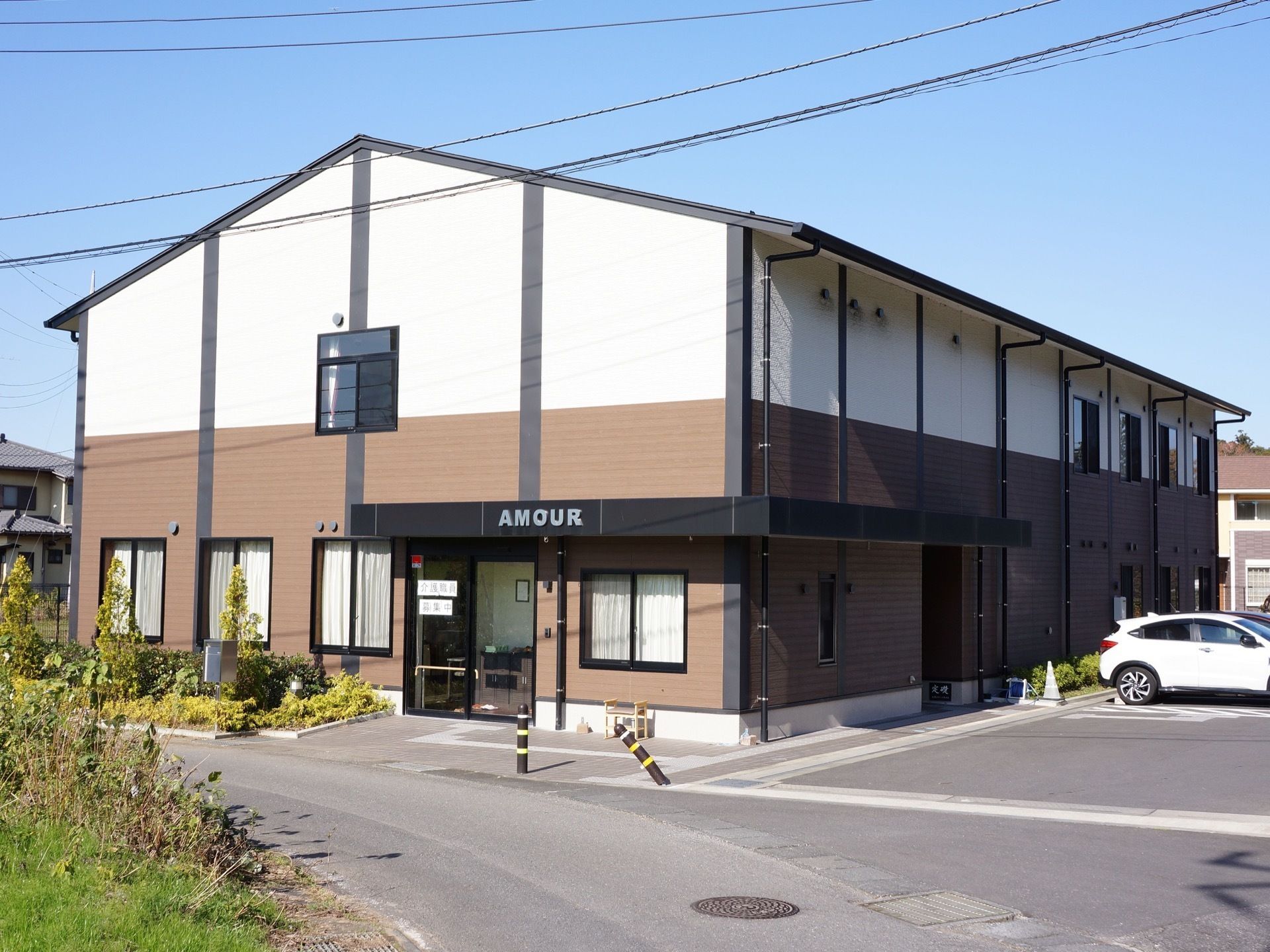 施設の建物は二階建てで、玄関の上部には大きく施設名を表示した屋根を設置している。建物の右側に駐車場がある。