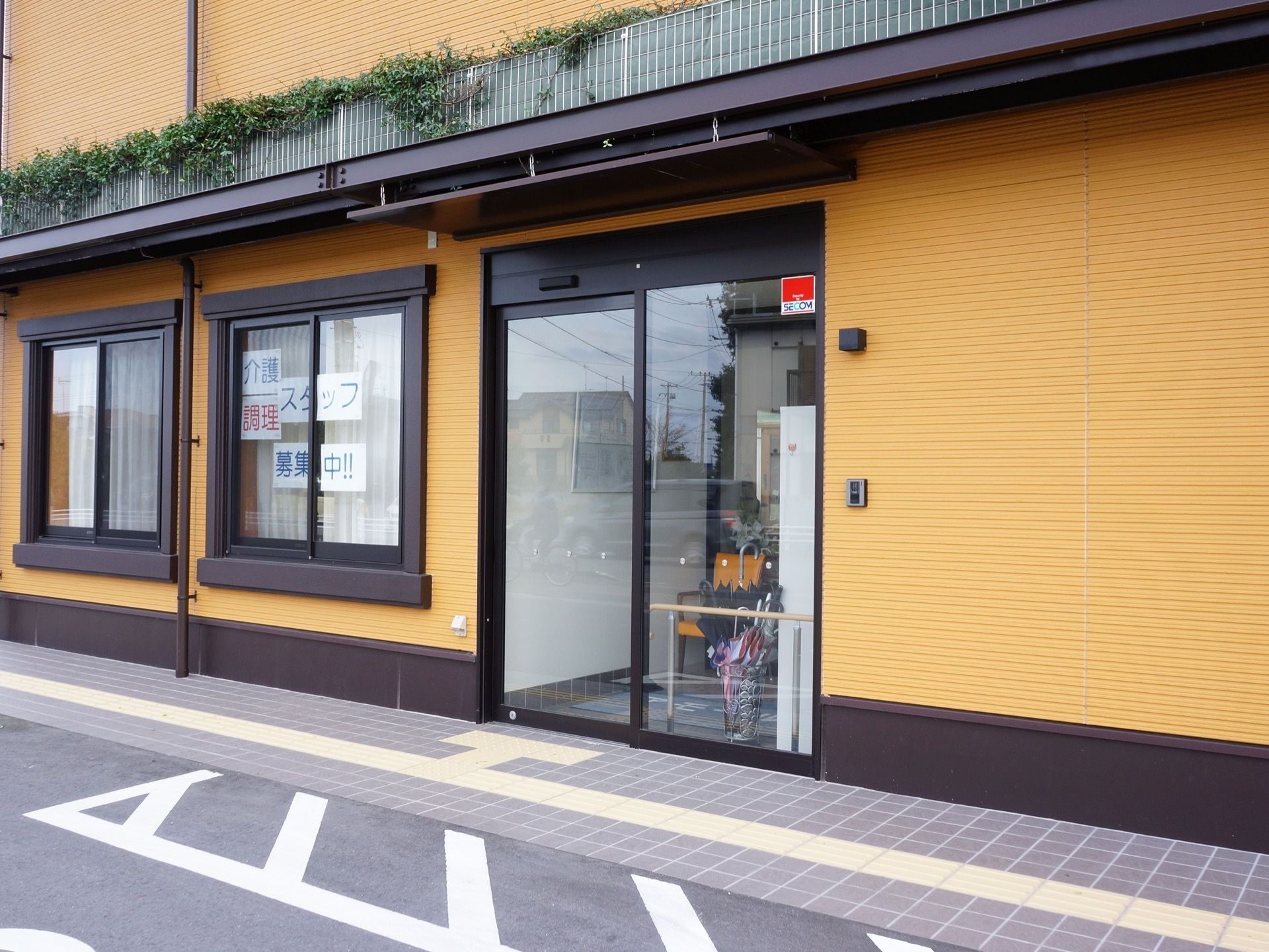 ガラス張りの自動ドアが設置された玄関は、施設内が見えるので入りやすくなっている。扉の右側にはインターホンが設置されている。