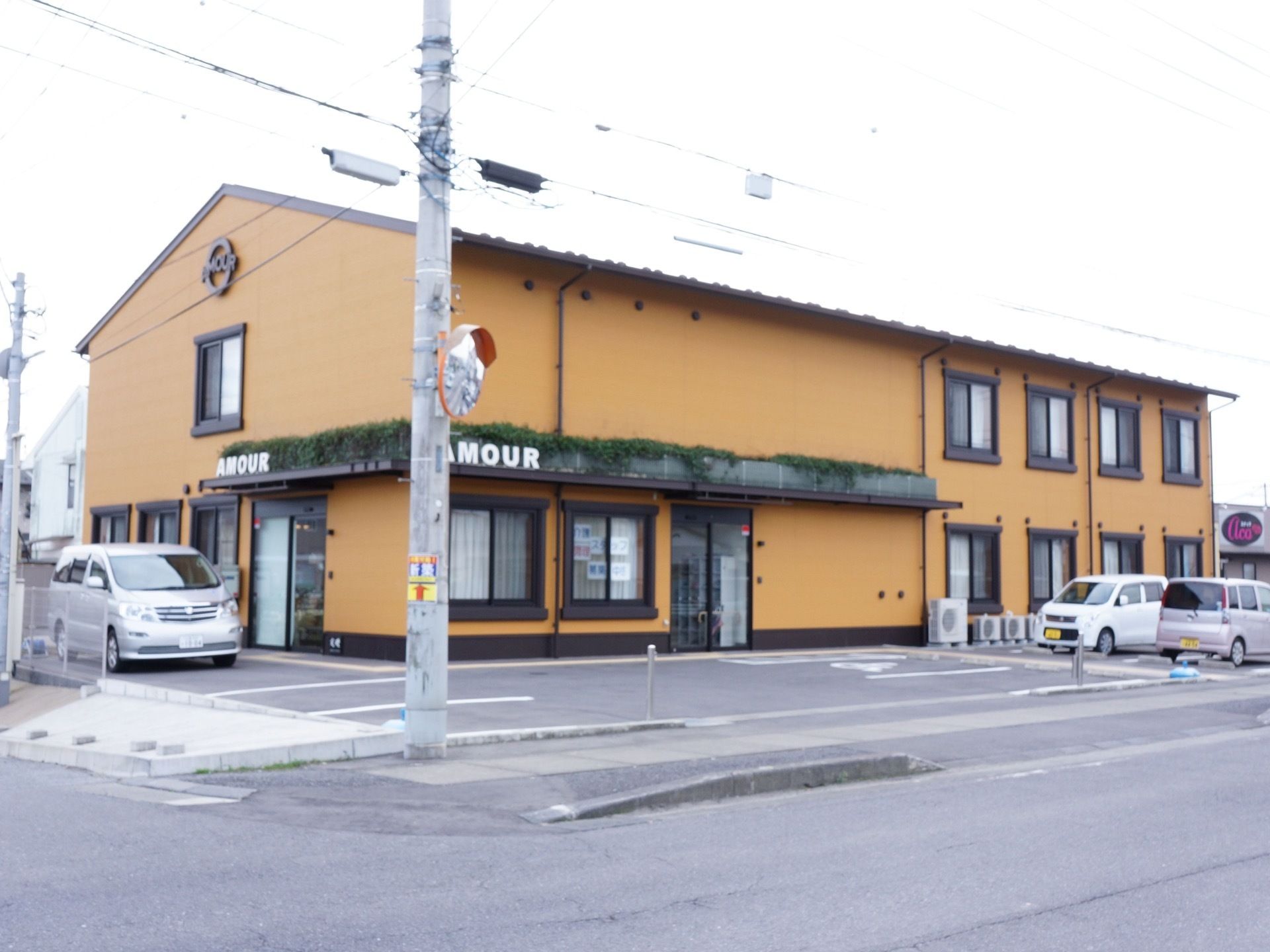 建物は2階建てで、施設名がブラウンの外壁にアルファベットで書かれている。玄関の扉はガラス張りの自動ドアになっている。