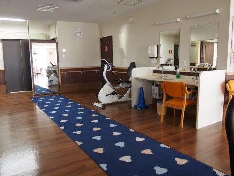 歩行訓練、器具を使用しての訓練の場となっている。奥の鏡の設置により、入居者様及びサポーターの姿等の見える管理が可能となっている。