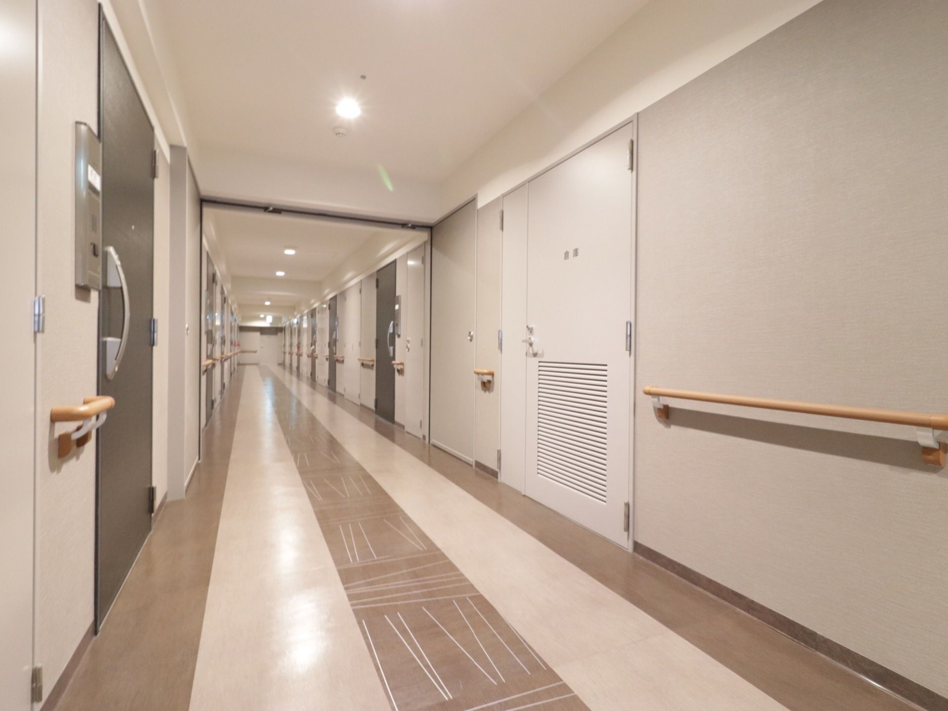 横幅の広い廊下が続いている。両側に居室の扉が並び、各部屋にインターホンがついている。壁には手すりが設置されている。