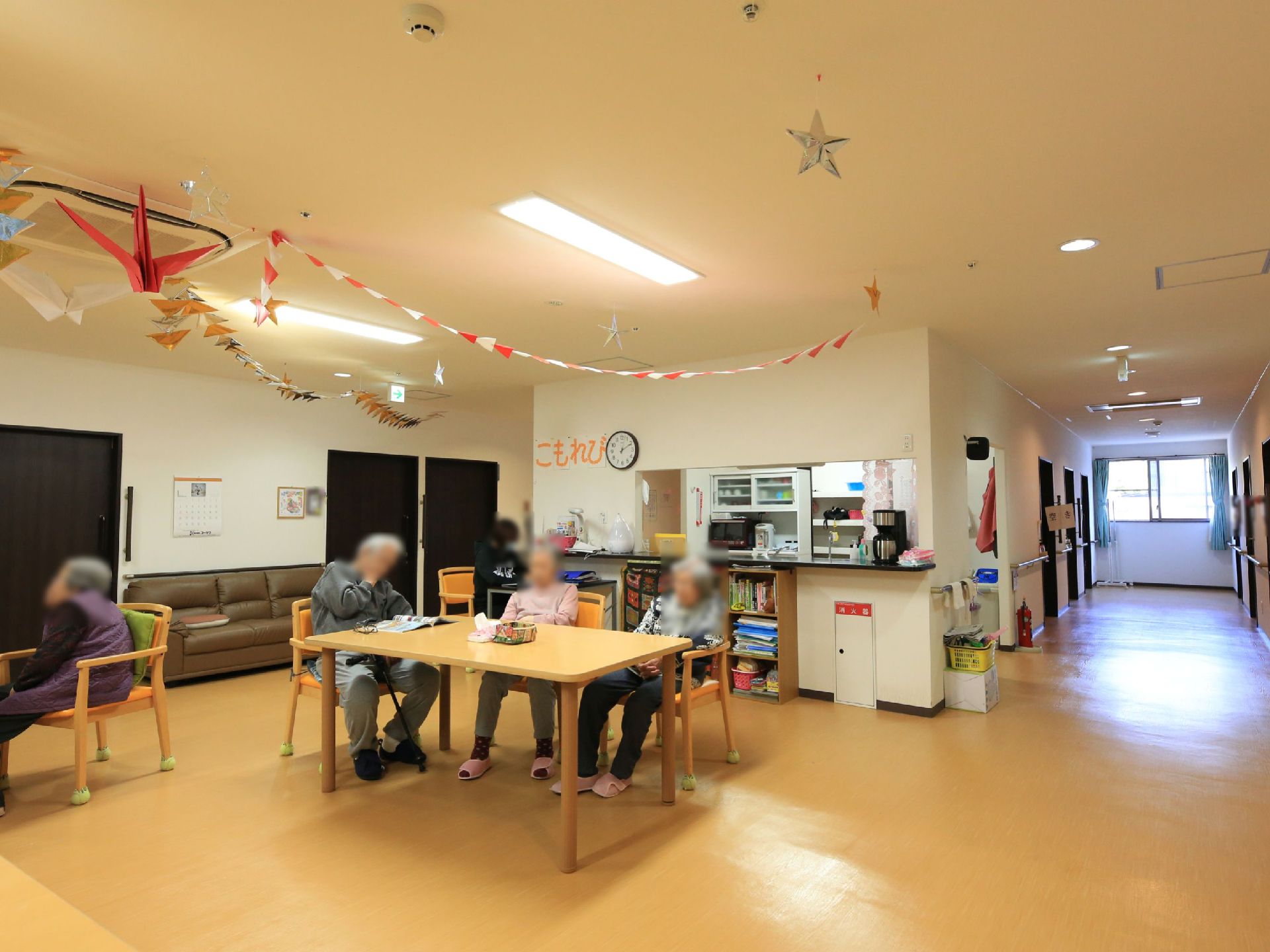 対面式のキッチンがある食堂で、入居者様が思い思いの時間を過ごしている。カウンターにはコーヒーメーカーが置かれている。