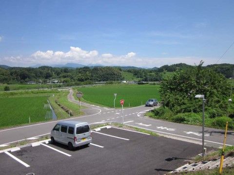 施設の広い駐車場と周辺に田んぼが広がるのどかな風景