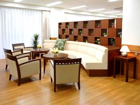 二つの丸テーブルの周囲に、ソファー椅子と白い長椅子が設置されているリビング