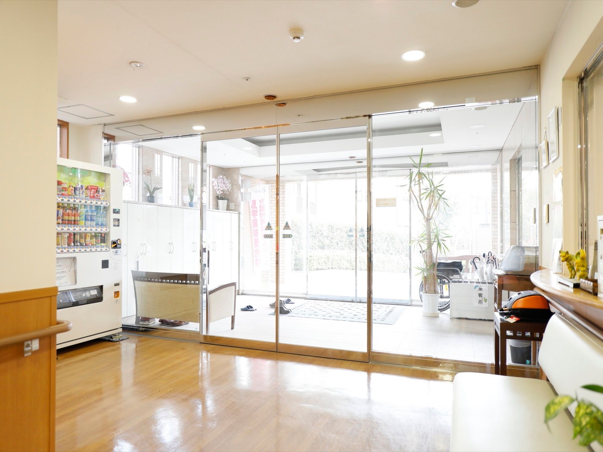 施設の入口は大きなガラス張りになっており、外光がそのまま施設内へと入ってきている。傘立てや長椅子、自動販売機が設置されている。