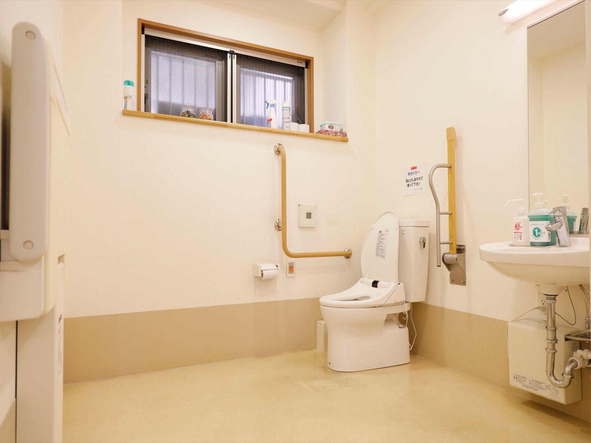 明るく、スペースがしっかりと確保されたトイレには、鏡付きの洗面台と、両脇に手すりが用意された便器が設置されている。