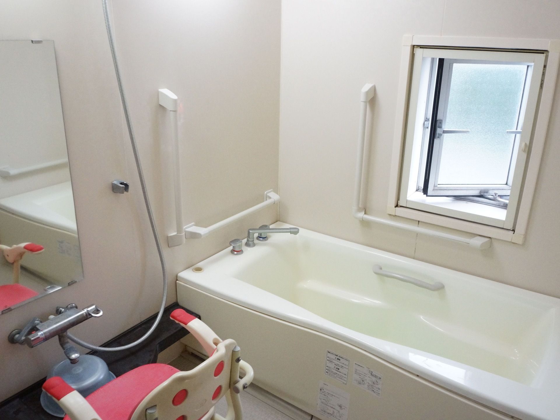 バスルームには広々としたバスタブがあり、壁に手すりが取り付けられている。また洗い場にはシャワーチェアが置かれている。
