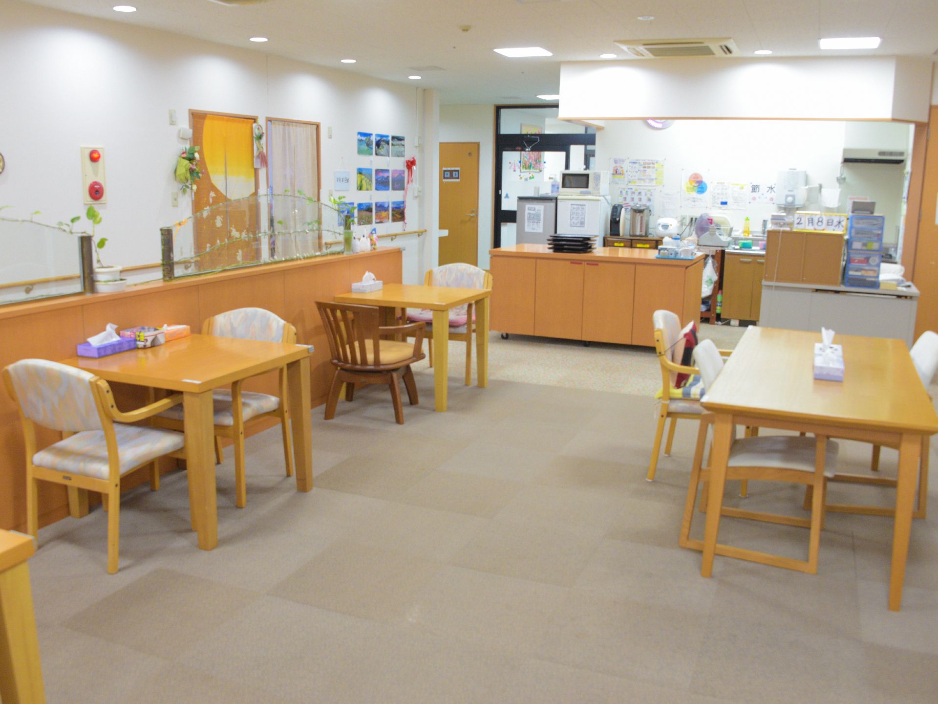食堂には、木製のテーブルと肘付きの椅子が置いてある。カウンターにはポットや炊飯器などが台所にある。フードレンジがある。