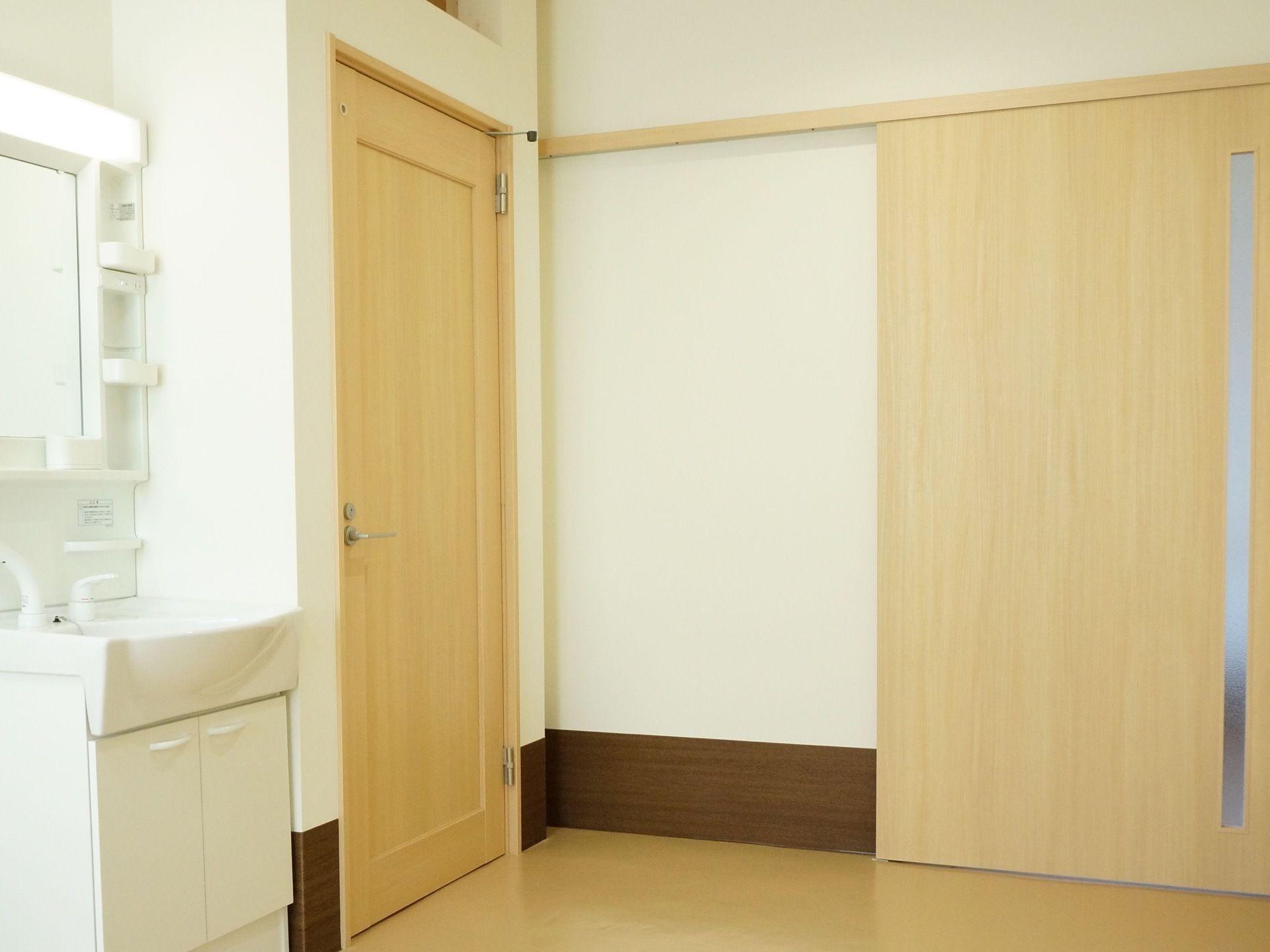 白を基調とした明るい居室のドアは木製の引き戸である。そばに洗面台があるので帰宅後はすぐに手洗いうがいができる。