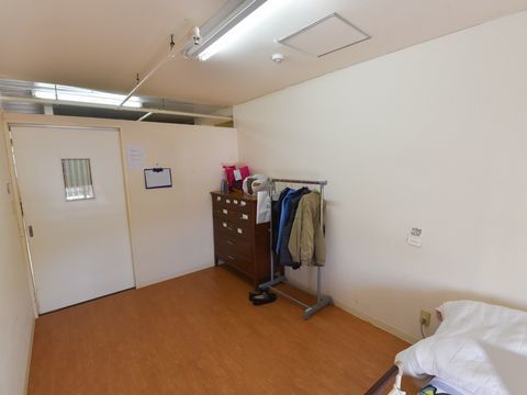 ハンガーラックとタンスが置かれている、引き戸がついた居室の様子