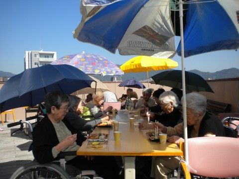 屋外のウッドデッキスペースで食事を楽しむ入居者様の様子