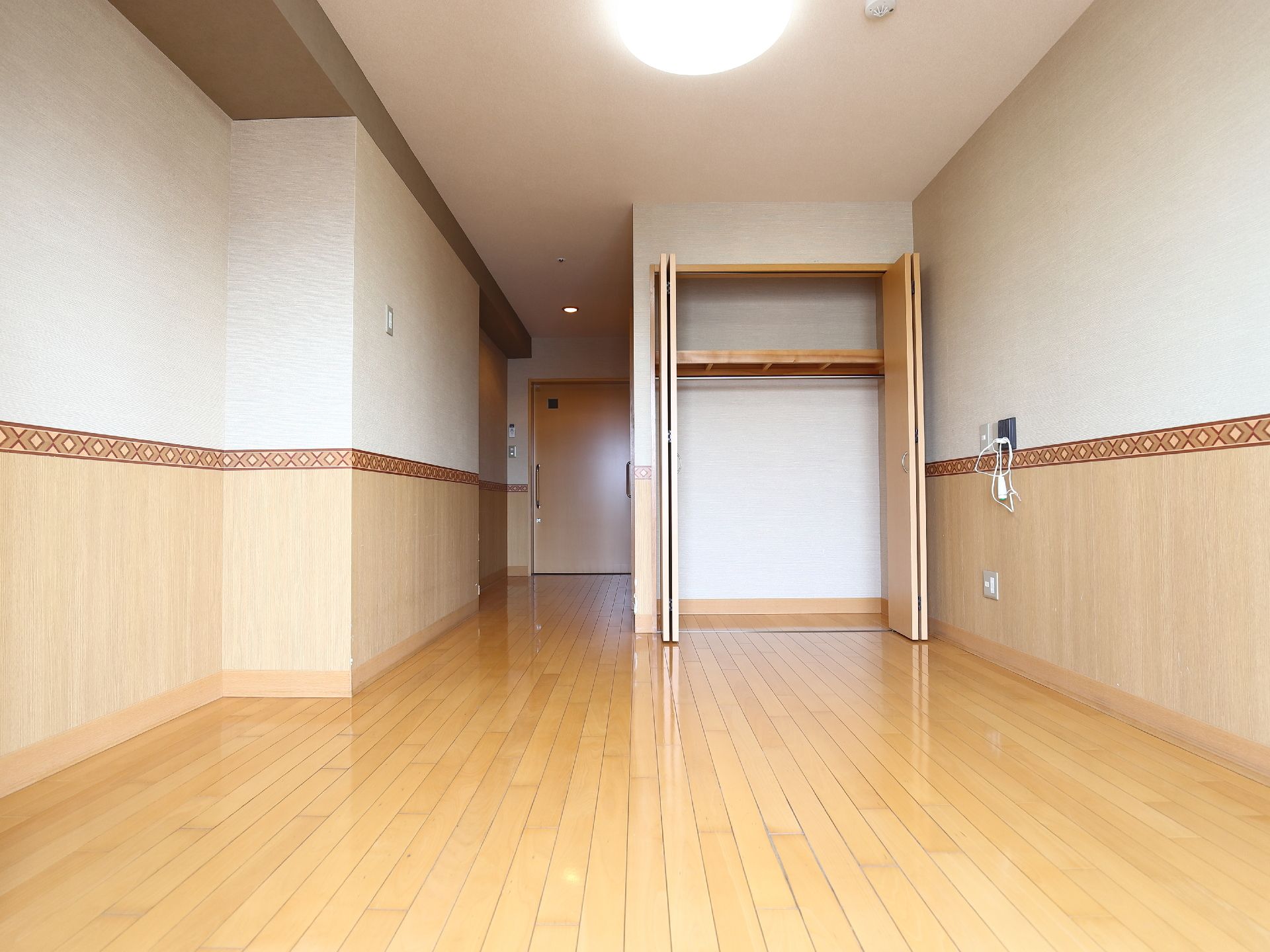 広々として明るい居室は収納スペースが充実している。壁紙は上半分が白、下半分が淡い木目調となっている。