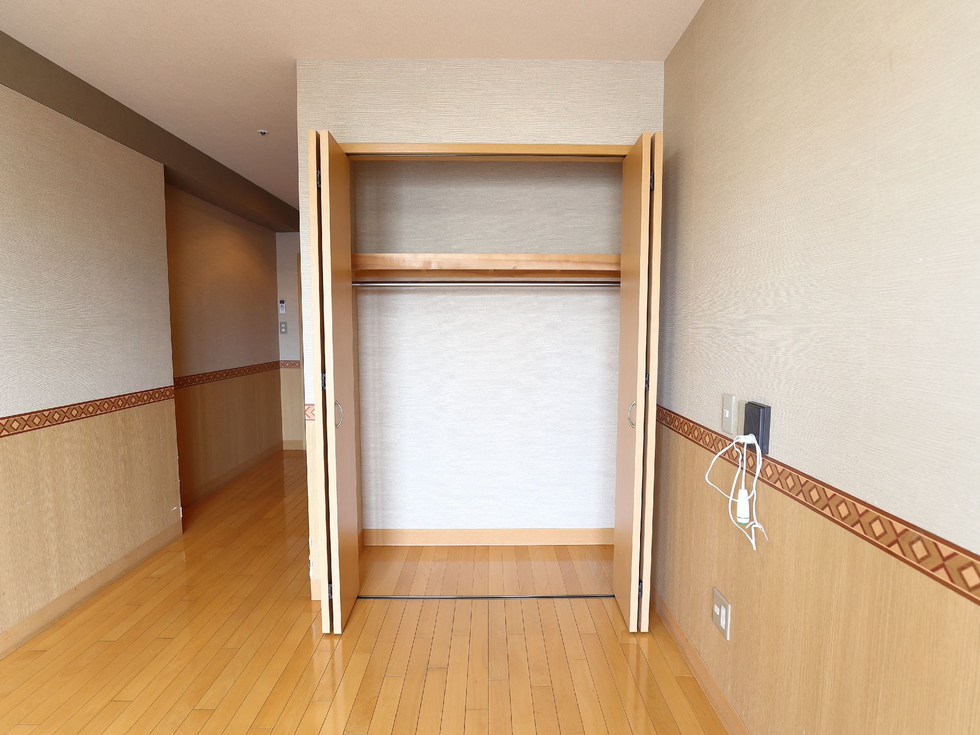 個室はブラウンを基調としたインテリアである。部屋の角部分にはクローゼットがあり、中には棚が1つとバーが設けられている。