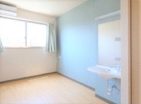 大きな鏡と洗面台が室内に設置されている、壁の一部が水色のさわやかな印象の居室