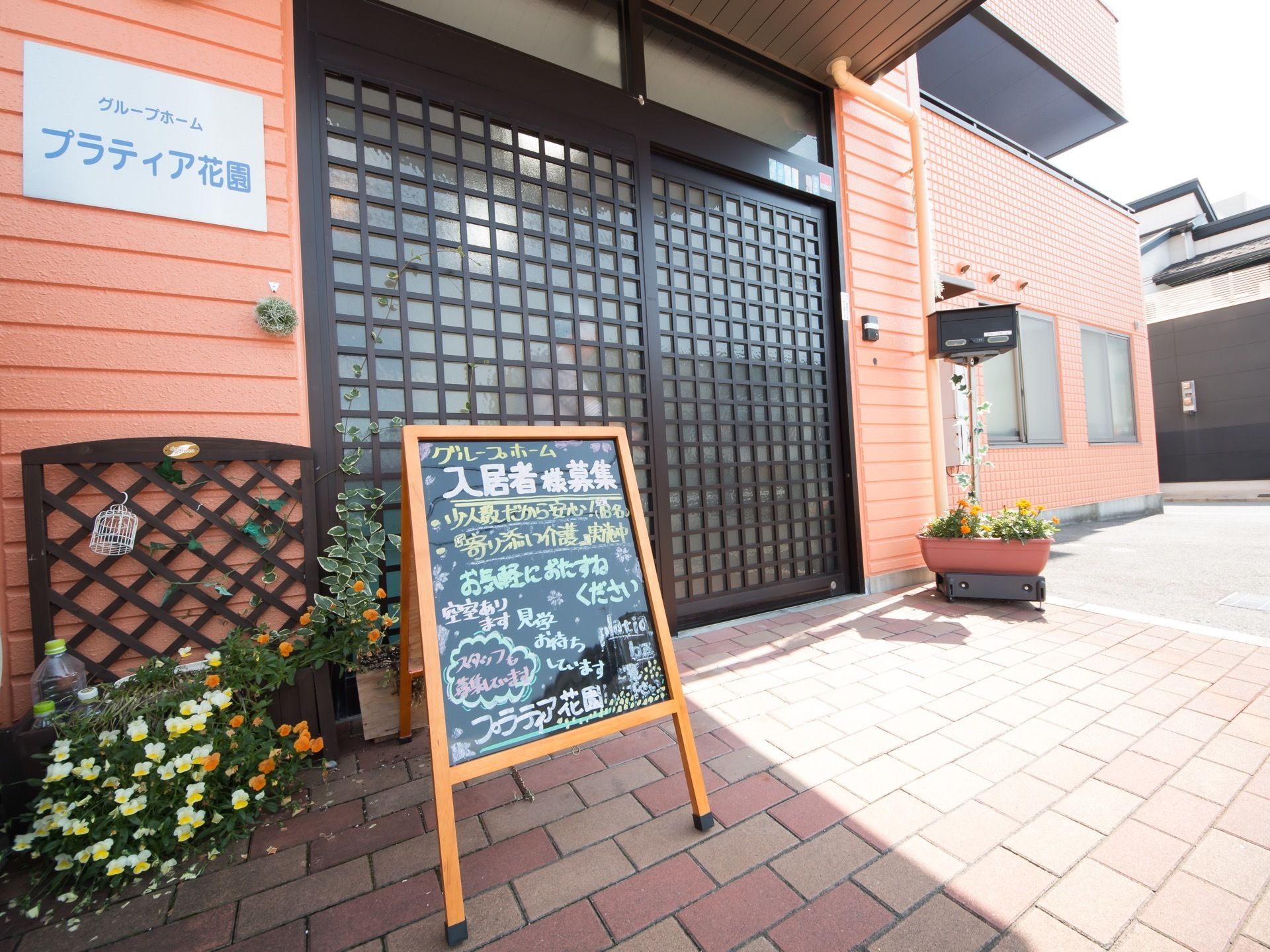 出入口に手書きのメッセージボードを設置している。玄関には屋根があり、スライド式のドアには和モダンな印象がある。