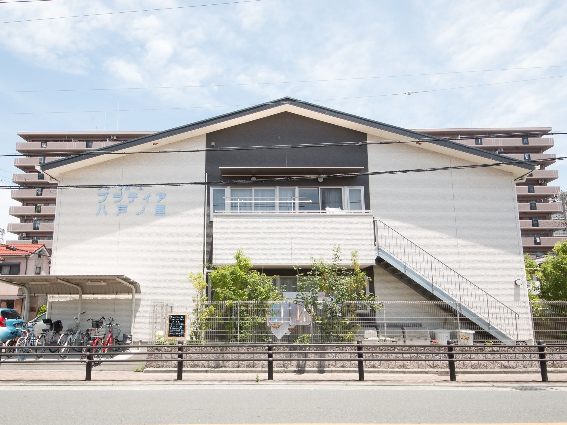 道路に面しており、駐輪場が設けられている。2階へと上がる外階段がある。ベランダには洗濯竿が設置されている。
