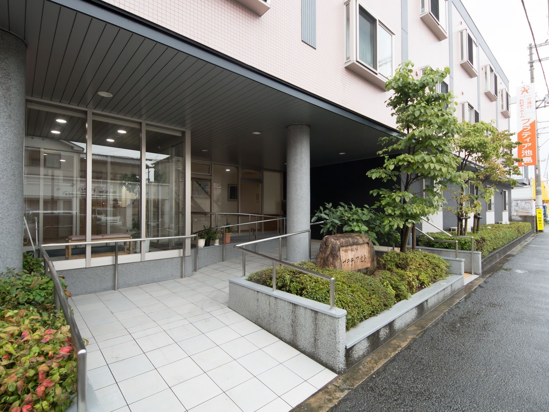 玄関を外から見た様子である。出入口にはスロープが設置されている。両側に手すりがついているため安心してご移動いただける。