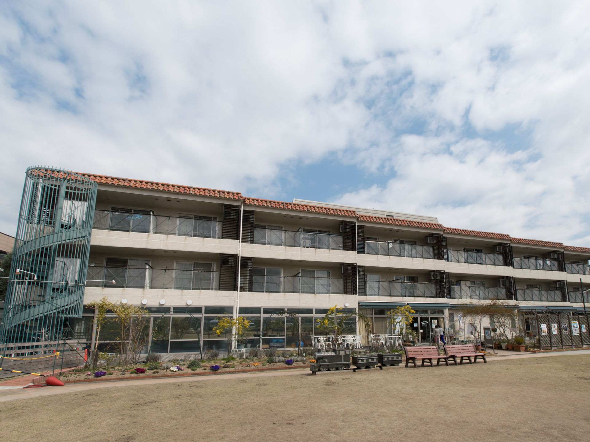学校の校舎のような施設外観。敷地内はアスファルトの少ないグラウンドのような造りになっている。