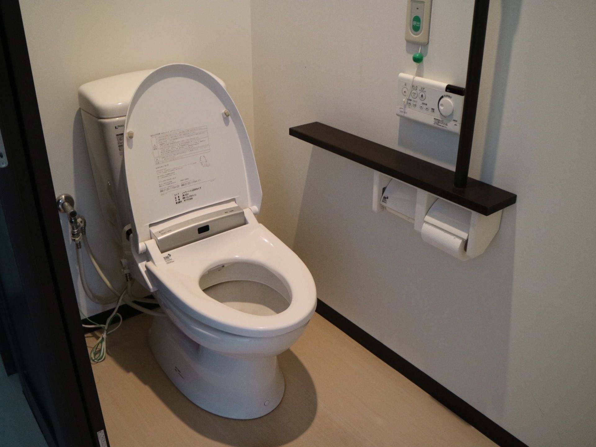 引き戸で仕切られた空間に、蓋やタンクが取り付けられた洋式便器が据えてある。壁面には、トイレ操作用のボタンやナースコールが取り付けられている。
