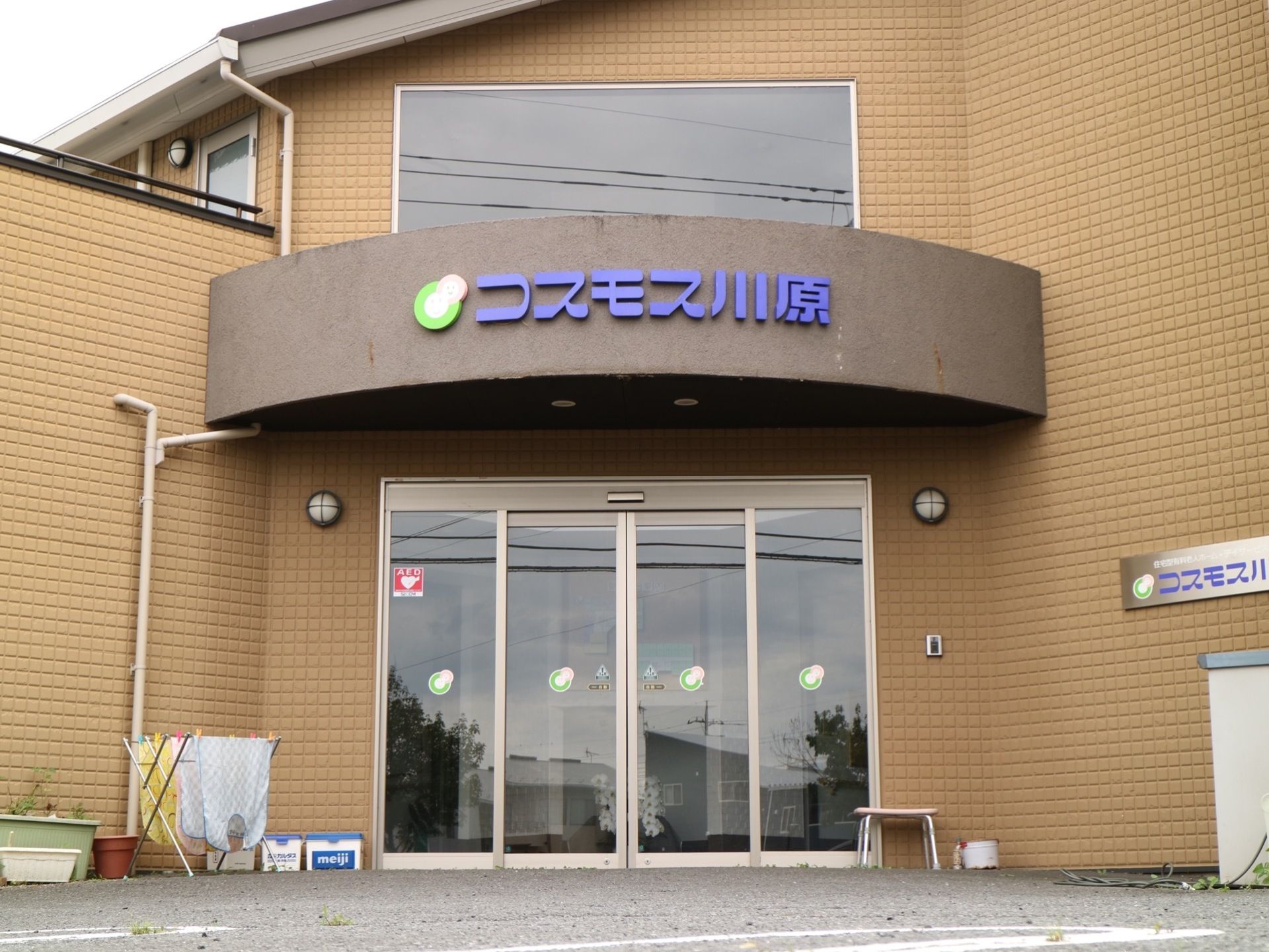 Ｌ字型の建物の正面。ガラス戸の自動ドアの上に、丸みを帯びた屋根が掛けられており、施設名称が明示されている。