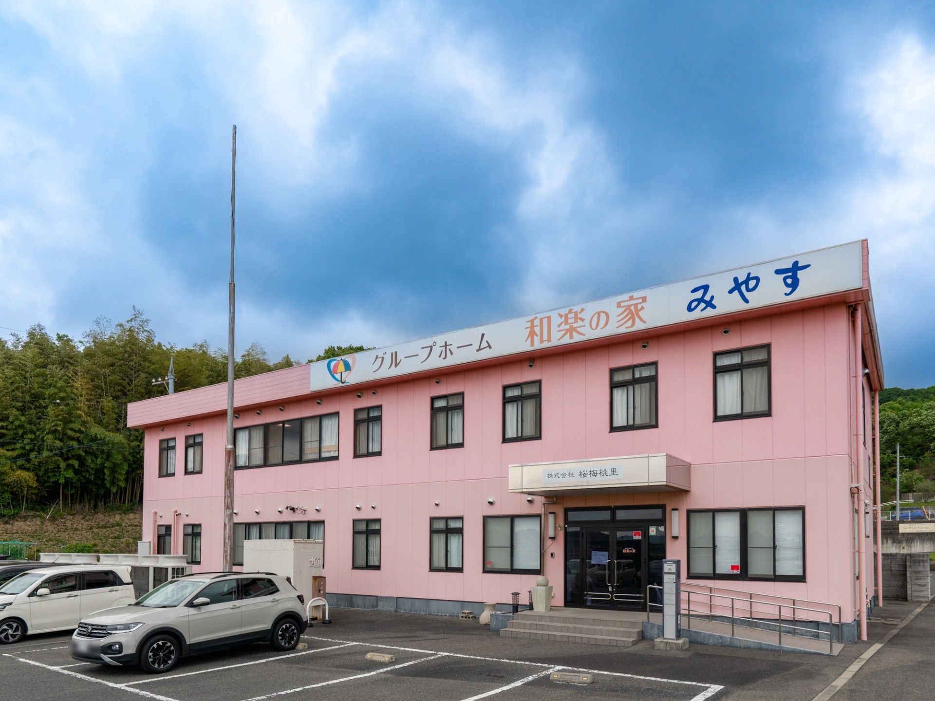 車椅子に座って微笑む高齢女性と付き添う男性ヘルパー