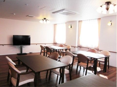 濃い茶色床に置かれた家具と薄いピンクの張地の椅子で、シックな雰囲気の多目的室