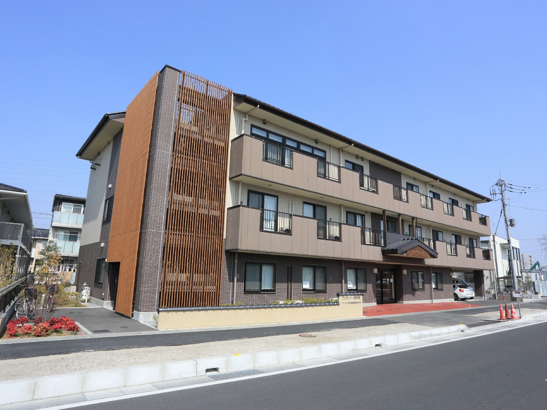 赤いエントランスが印象的な施設外観。敷地内は車いすでのご利用も安心して行えるよう整備されている。