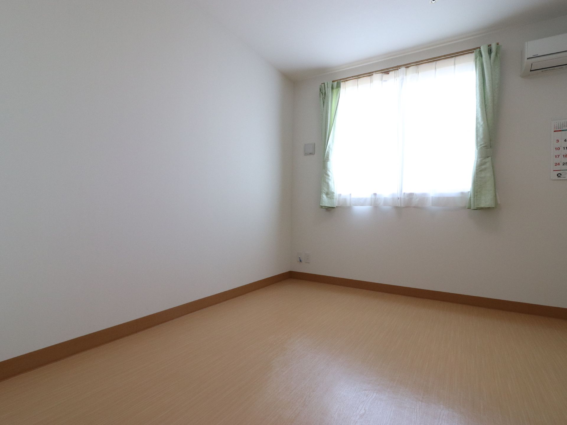 窓の付いた日差しの入る明るい居室の様子。広々としたフローリングの部屋では、車椅子の方にも楽に移動して頂ける。