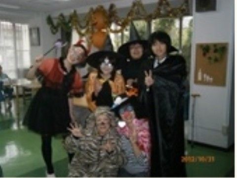 ハローウィンの仮装をして、飾りのついた室内でポーズをしている6人の人物