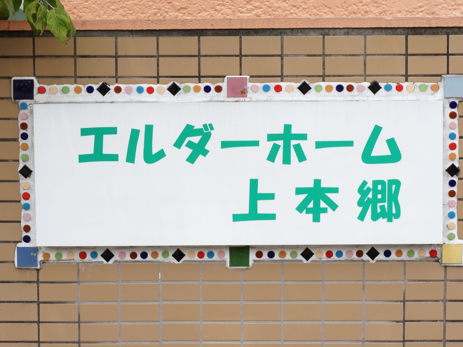 施設の門に設置されている施設名の表札の周りには色とりどりのタイルがはめ込まれ、楽しい印象を与えている。