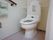 トイレに張られたタイルは白と落ち着いたピンク。個室内には手すりが複数設置され、安全に使用できるよう配慮されている。