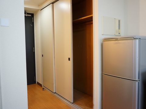 白い壁にブラウンの床の部屋で、引き戸が開いて中が見えている押し入れ