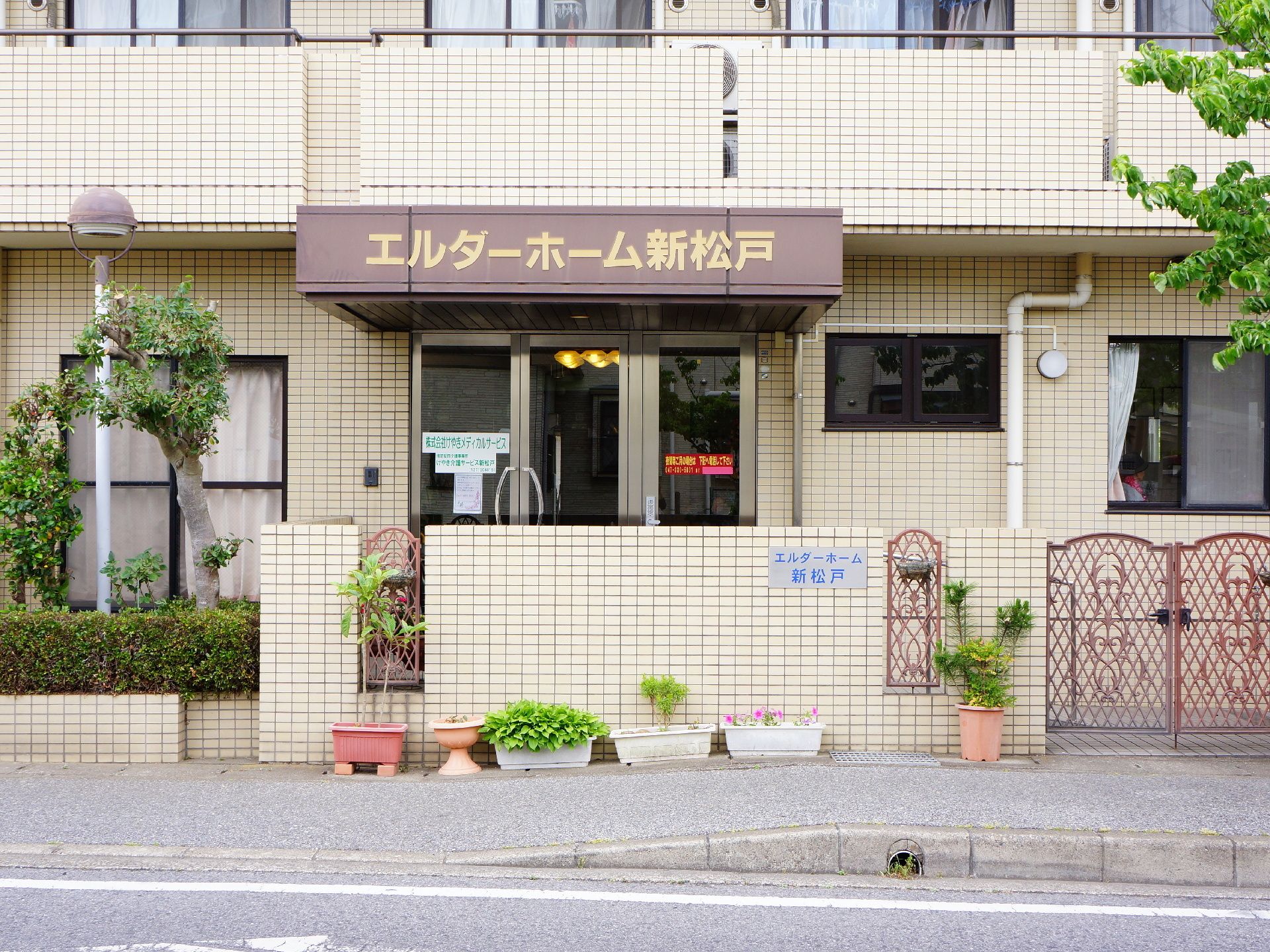 門も外壁にもクリーム色のタイルが使われている、マンションのような外観。ドアの上には大きくし説明が書かれている。