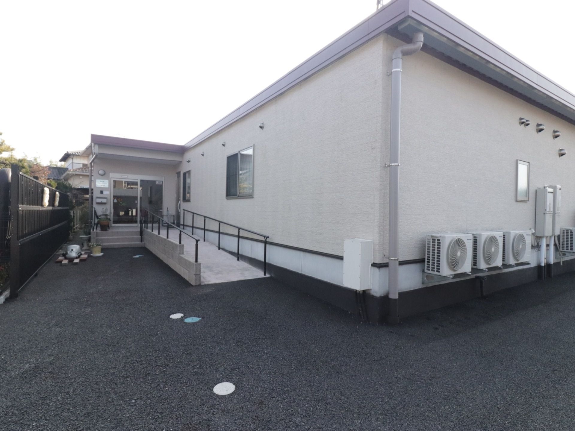 施設の建物は平屋で、壁は白色をしている。建物の左奥に玄関がある。施設の周囲は、アスファルトが敷かれている。