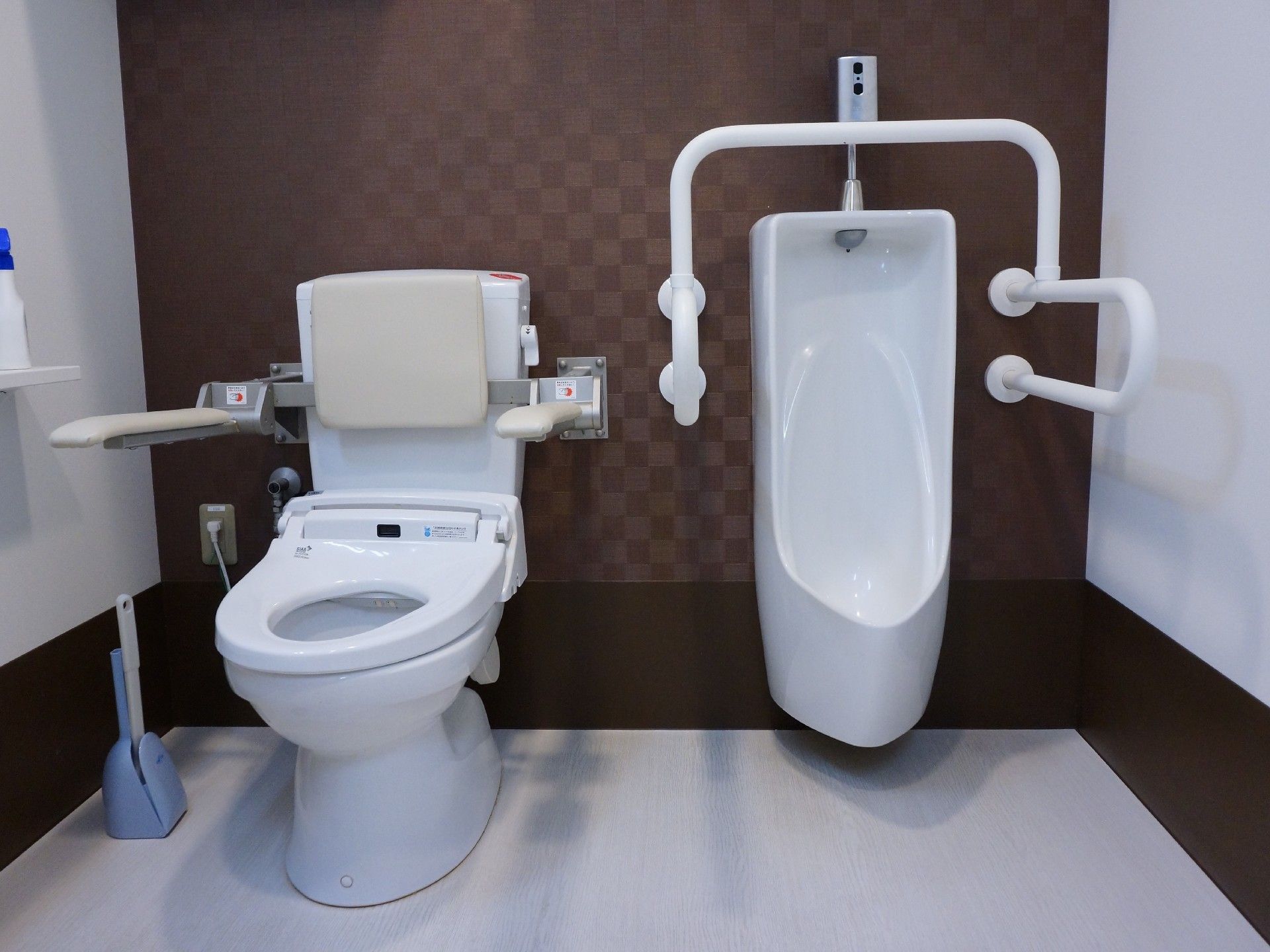 男性用の小便器と、洋式のトイレが隣り合わせに設置されている。小便器には、白い手すり、洋式トイレには背もたれが付いている。