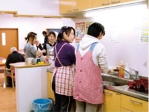 食堂との間にカウンターがある流し台で作業をしているエプロンをかけた2人の女性