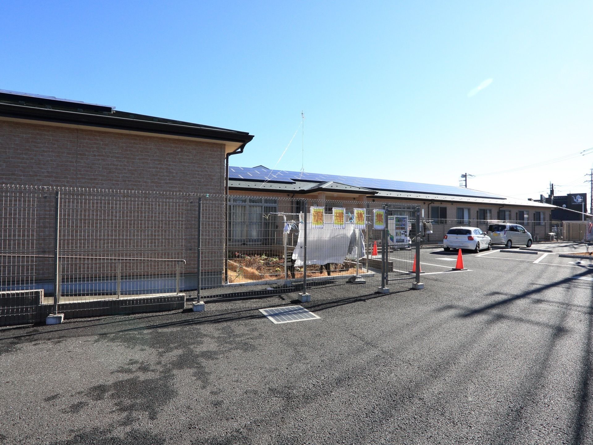 グループホームの建物はブラウン色の外壁で、平屋建てとなっている。また敷地内には広々とした駐車スペースが確保されている。