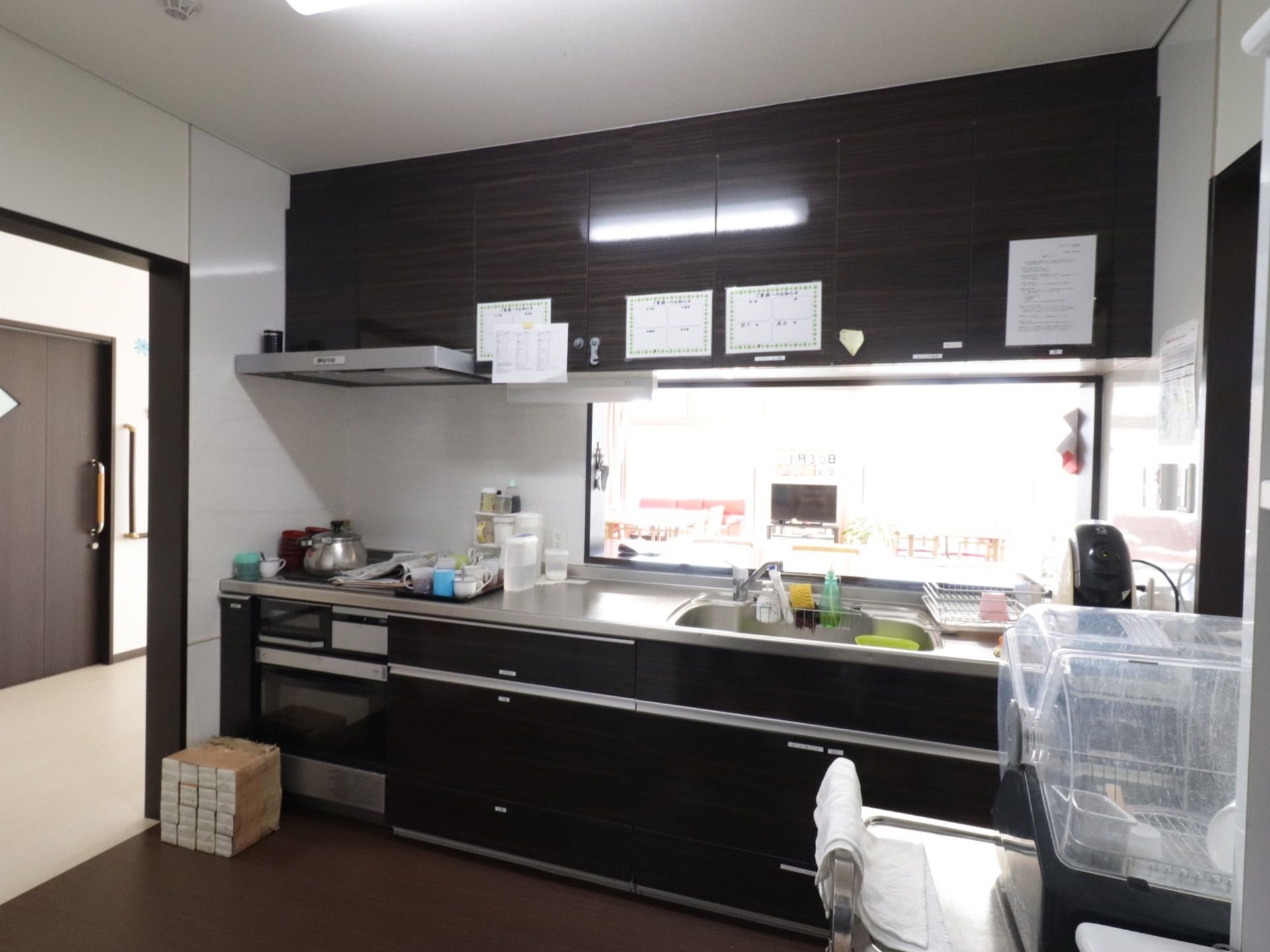 キッチンの様子。対面システムキッチンで、下部と上部に扉付きの棚がいくつもある。エスプレッソマシーンも置かれている。