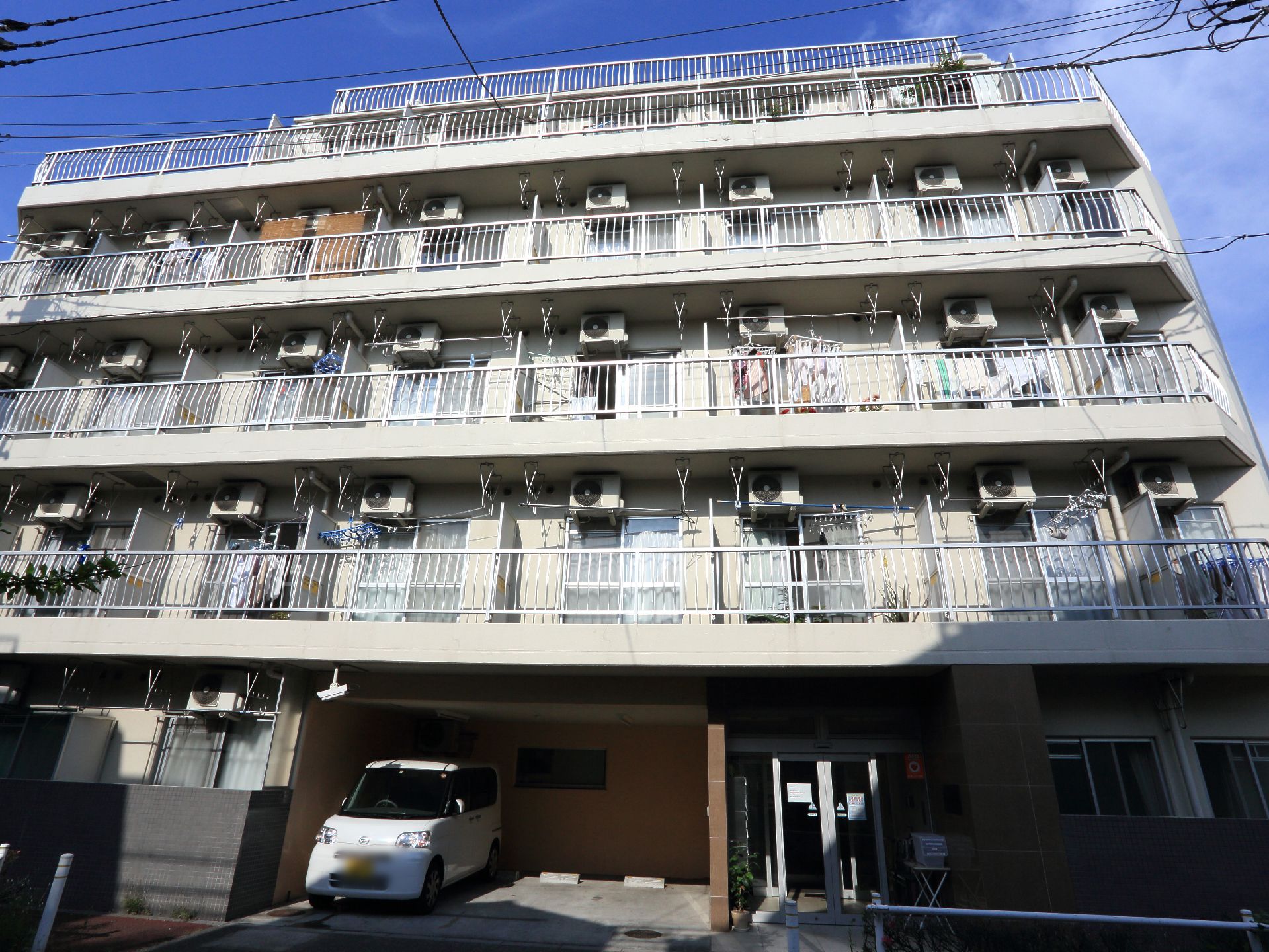 施設は5階建ての建物で、ベランダにはエアコンの室外機があり、物干しざおをかけられるようになっている。駐車スペースもある。