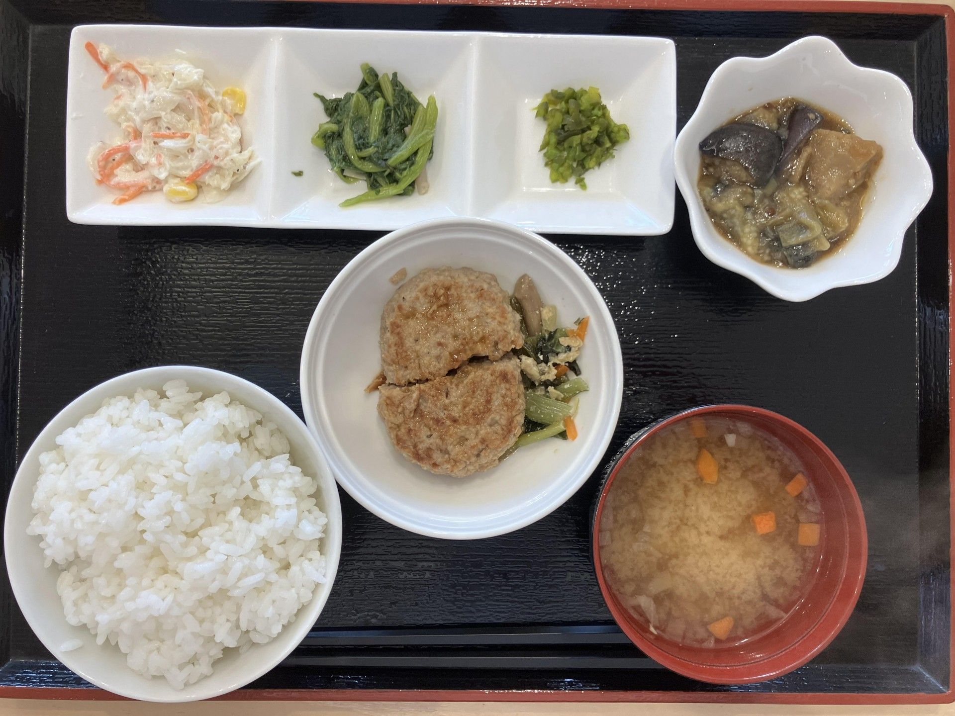 ちらし寿司風のご飯に味噌汁が置かれ、奥におかずや小鉢が並んでいる食事例