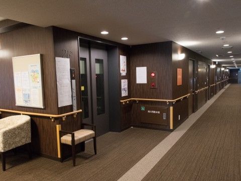 「グランメゾン迎賓館京都桂川」エレベーター。出入り口には、椅子が置いてあり、壁には手摺りがついております。