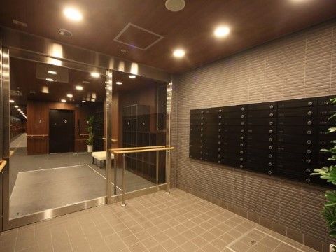 車椅子も余裕で通れる大きな玄関ドア。入り口には個別のポストも完備している。照明も明るく壁際には手すりがついている。