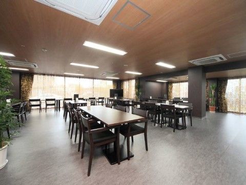 大きな窓が並ぶ明るい食堂。シックで落ち着いたテーブルセットがたくさんあり大人数でも食事ができる。車椅子の移動も楽にできるよう広々としている。