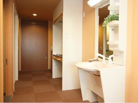 車椅子のままでも使いやすい洗面ボールが前に飛び出したタイプの洗面と手すりがついたキッチンが設置されている。