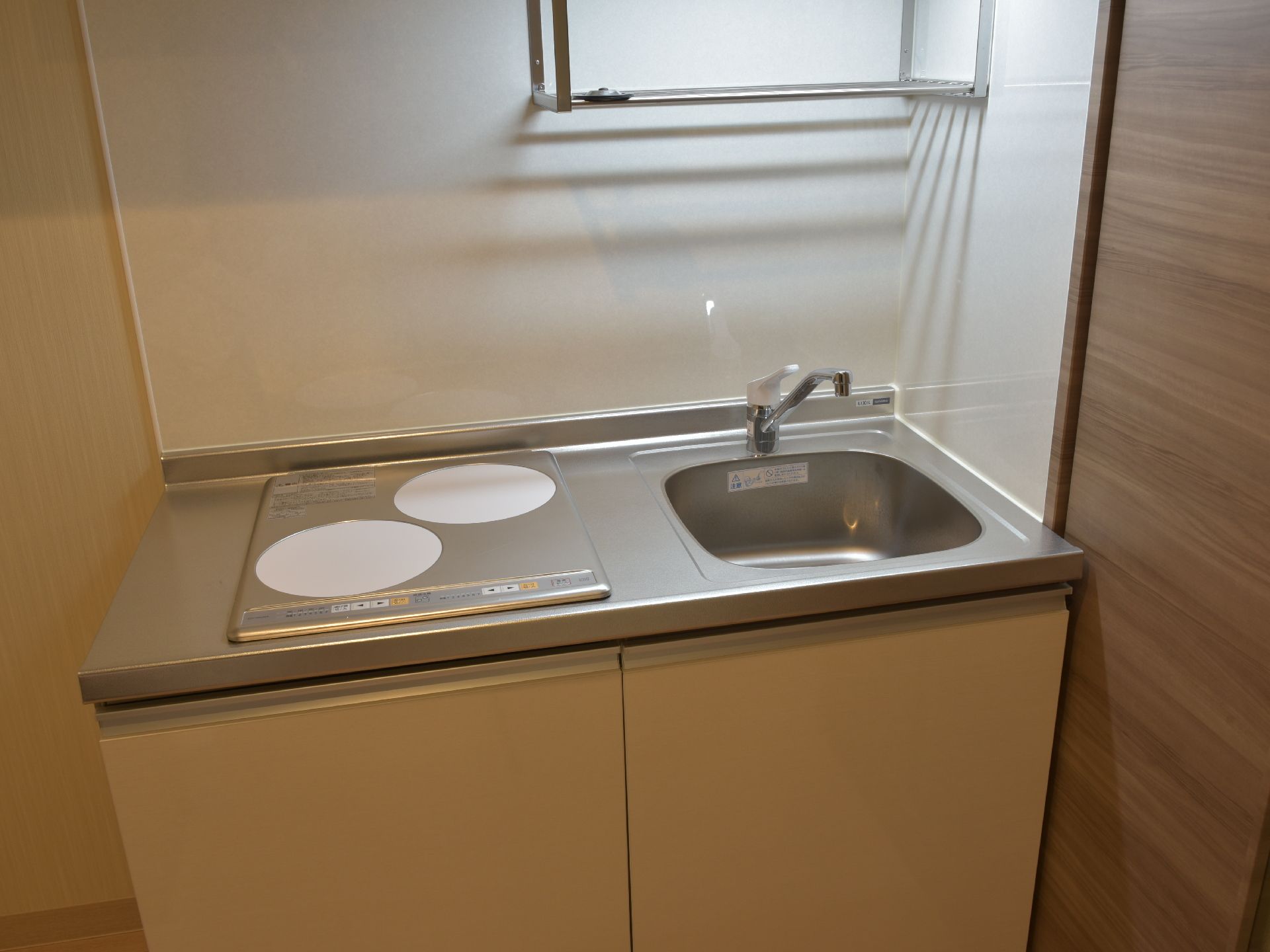 各お部屋には火を使わず安心なIHキッチンが設置されている。コンロは2口あり、下には収納がついている。丈夫にも棚があり、物が置ける。