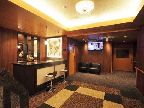 シックな色調にまとめられ、高級感のある空間。手前には重厚感のあるカウンター、奥には革張りの一人がけソファーが二つ置かれている。