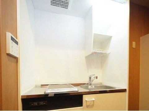 水道とHIタイプの電磁調理器を備えたミニキッチン。コンパクトながらも、物を置いておける棚が設置されている。