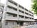 落ち着いた色調の外観で、4階建ての建物です。ガーデンチェアとテーブルがエントランス近くに設置されていて会話を楽しめる。