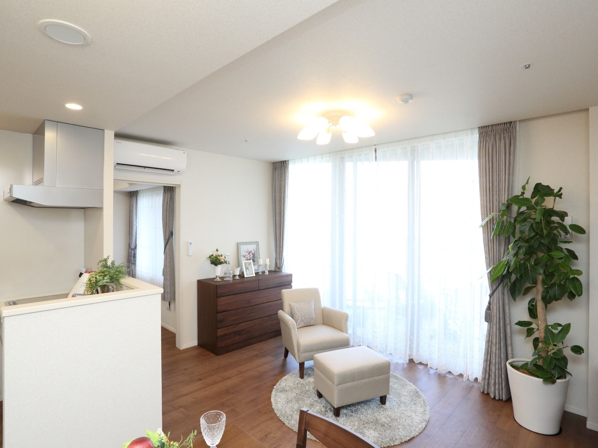 大きな窓があり陽の光が差し込む明るい部屋になっている。エアコンやキッチンの他、タンスや椅子などの家具も揃っている。